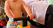Giovanni is registered to the contest to win money with this photo: adult, beard, blanket, carpet, child, couch, furniture, handlebar, happy, indoor, living_room, pants, person, play, shirtless, smile, toddler, toy_truck, window_light, yellow
