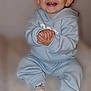 baby, child, smiling, happy, clapping, blue_hoodie, sitting, cozy, infant, cute, toothy_smile, hands, feet, socks, indoor, portrait, young_child, joyful, expression, soft_background