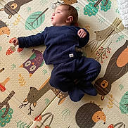 Côme participe au concours pour gagner de l'argent avec cette photo : baby, infant, blue_clothing, knitwear, play_mat, animal_print, forest_theme, hedgehog, bear, deer, owl, mushroom, leaf, child, cute, lying_down, indoor, soft_texture, colorful, curious