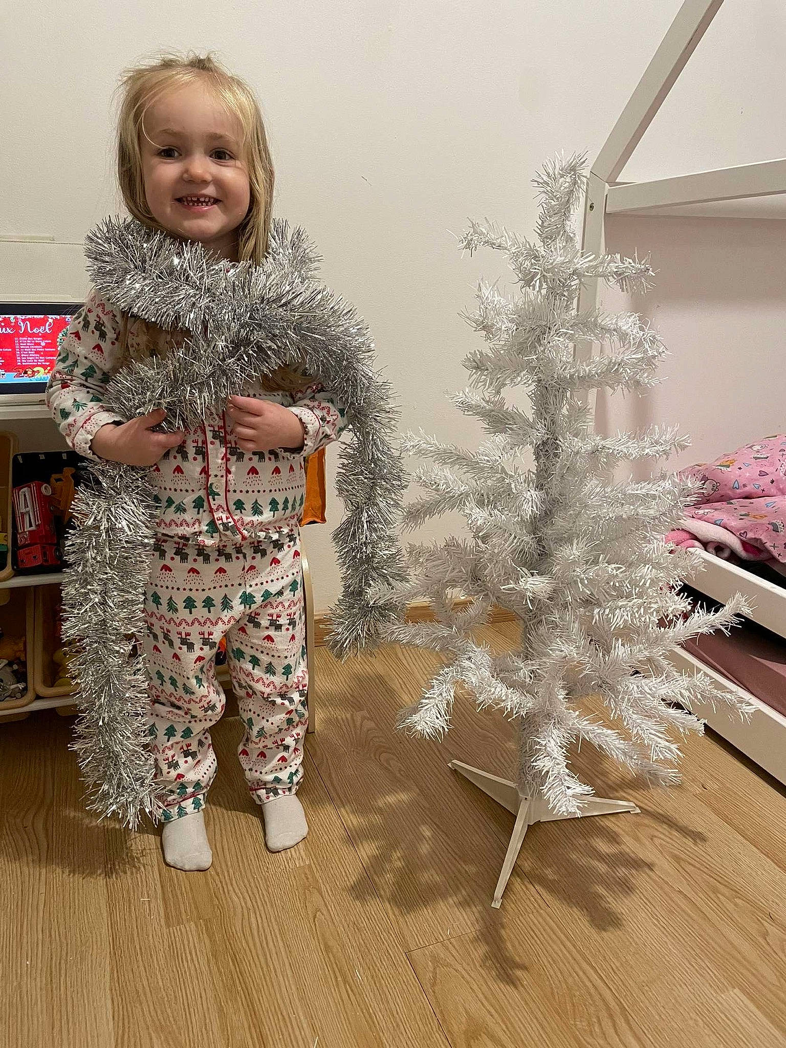 Giulia participe au concours pour gagner de l'argent avec cette photo : baby_toddler_clothing, bookcase, christmas_ornament, christmas_tree, conifer, event, flooring, hardwood, holiday, joy, ornament, pattern, person, shelf, sleeve, smile, toddler, tree, twig, winter