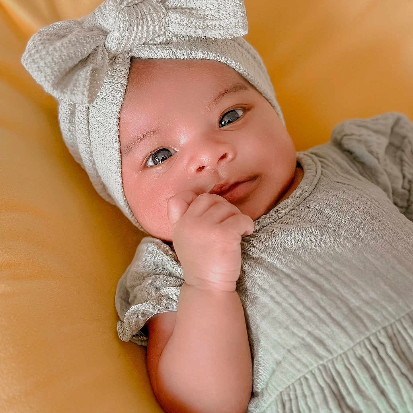 Ellie is registered to the contest to win money with this photo: baby, beanie, bodypart, bonnet, cap, clothing, couch, face, finger, furniture, hand, happy, hat, head, hood, newborn, person, photography, portrait, smile