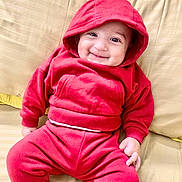 Nofal joined the competition — help win amazing prizes! baby, child, smile, red_hoodie, red_pants, couch, beige_couch, indoors, happy, cute, infant, clothing, sitting, portrait, face, hood, person, young_child, cozy, casual
