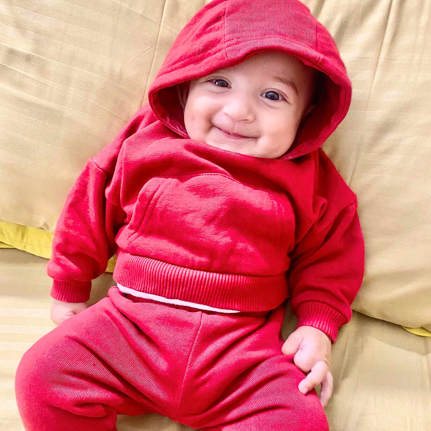 Nofal joined the competition — help win amazing prizes! baby, beige_couch, casual, child, clothing, couch, cozy, cute, face, happy, hood, indoors, infant, person, portrait, red_hoodie, red_pants, sitting, smile, young_child