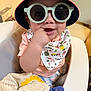 Rayleigh Lucas is registered to the contest to win money with this photo: baby, child, sunglasses, hat, bucket_hat, bib, high_chair, indoor, smiling, cute, hand, chewing, toy, plush, clothing, face, person, infant, happy, casual