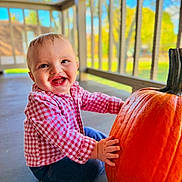 Austin is registered to the contest to win money with this photo: baby, child, pumpkin, porch, smiling, happy, red_checkered_shirt, blue_jeans, outdoor, daylight, face, hands, sitting, wooden_railings, fall, seasonal, cute, cheerful, infant, nature