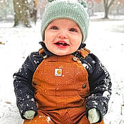 Austin is registered to the contest to win money with this photo: baby, child, clothing, cold, cute, happy, hat, knit_hat, mittens, nature, outdoor, overalls, portrait, seasonal, sitting, smiling, snow, snowflakes, trees, winter