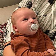 Anaé a rejoint le concours — aidez-le/la à gagner de superbes lots ! baby, pacifier, infant, child, person, clothing, patterned_shirt, arm, holding, indoor, comfort, cute, closeup, face, young, warm_clothing, striped_shirt, sleepy, relaxed, skin