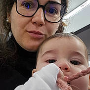 Marcio participe au concours pour gagner de l'argent avec cette photo : baby, casual, chewing, child, close_up, clothing, curious, expression, face, glasses, hair, hand, holding, indoor, knitted_string, light, person, portrait, skin, woman