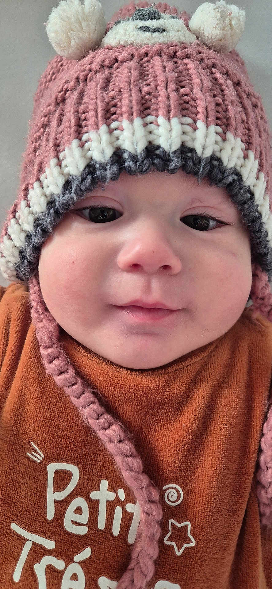 Marcio participe au concours pour gagner de l'argent avec cette photo : apparel, baby, brown_clothing, child, chubby_cheeks, close_up, cute, expression, face, hat, headwear, indoor, infant, knitted_hat, pom_poms, portrait, soft_texture, warm_clothing, winter_hat, young_child