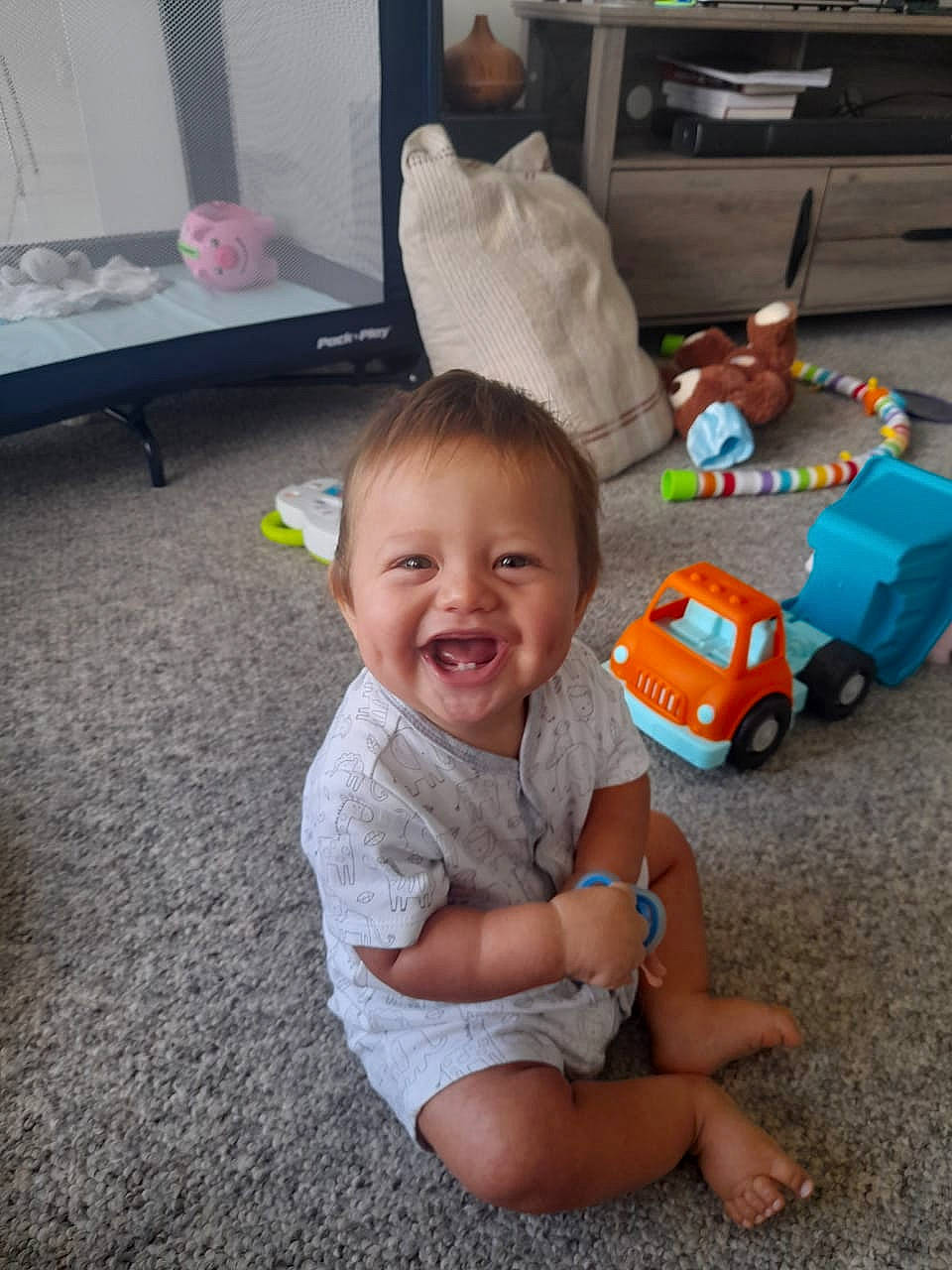 Richie is registered to the contest to win money with this photo: baby, baby_toddler_clothing, child, floor, flooring, foot, fun, happy, head, joy, person, play, riding_toy, shorts, sitting, smile, t_shirt, tire, toddler, toy