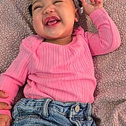 Joslynn is registered to the contest to win money with this photo: baby, child, smiling, pink_clothing, denim_shorts, laughing, happy, portrait, indoor, blanket, texture, cute, infant, person, face, joy, casual, fashion, head, hand