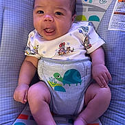 Dylan joined the competition — help win amazing prizes! baby, infant, child, onesie, cartoon, cute, smiling, sitting, baby_seat, colorful, plush, hand, foot, face, person, young_child, indoors, playful, expression, comfort