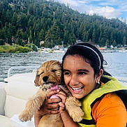 Cookie is registered to the contest to win money with this photo: adult, animal, canine, clothing, coat, dog, face, happy, head, jacket, lifejacket, person, pet, photography, plant, portrait, puppy, smile, tree, vest