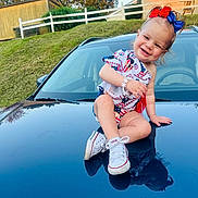 Allison joined the competition — help win amazing prizes! toddler, child, smiling, sitting, car, reflection, shoes, outdoor, grass, house, hair_bow, bracelet, happy, clothing, sidewalk, daylight, nature, portrait, cute, casual