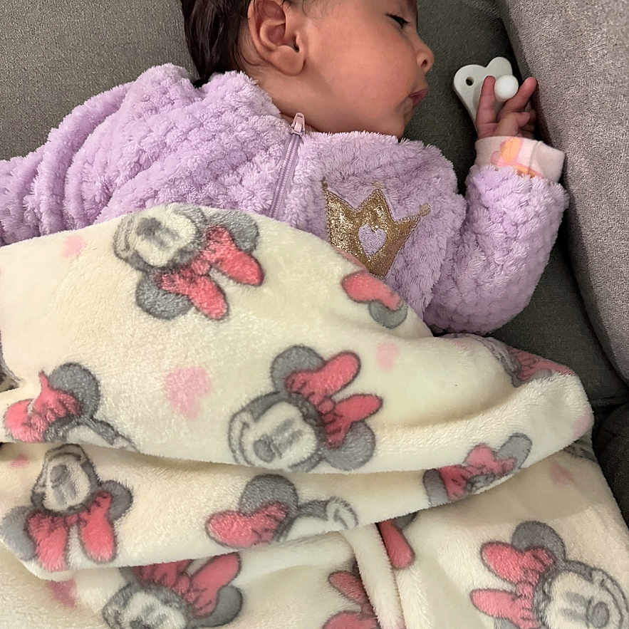 Melania joined the competition — help win amazing prizes! baby, blanket, child, comfort, couch, cozy, cute, face, hand, indoor, infant, minnie_mouse, nap, peaceful, purple_jacket, resting, sleeping, soft_fabric, warm, young_child