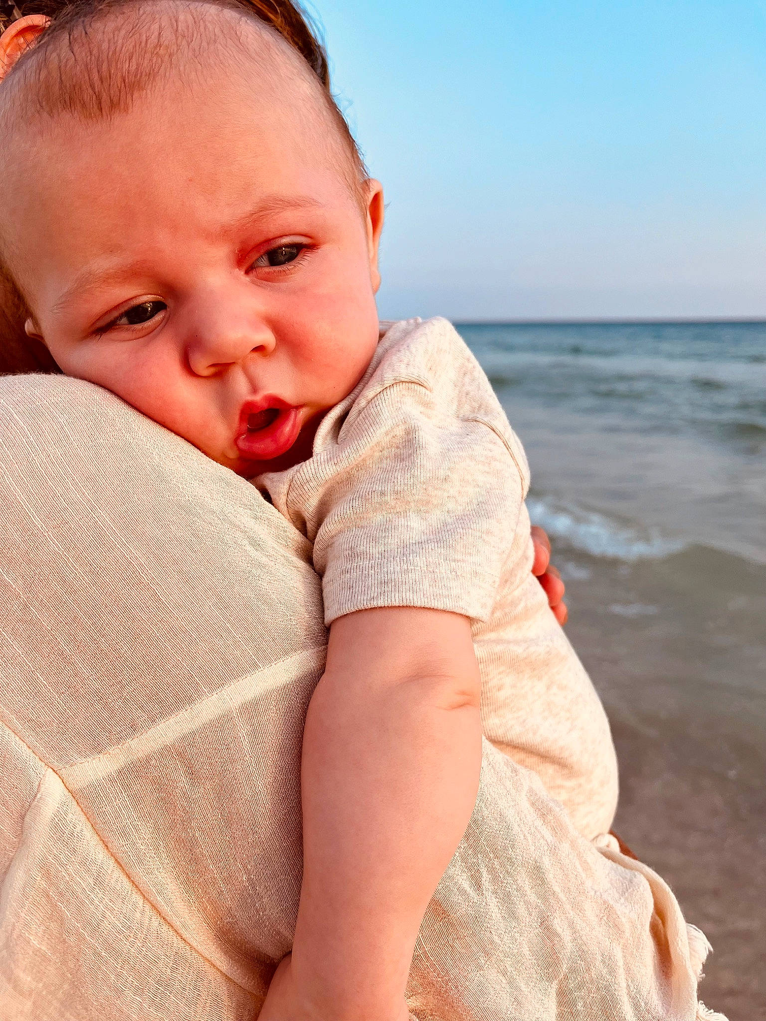 Creed is registered to the contest to win money with this photo: baby, baby_toddler_clothing, beach, child, comfort, flash_photography, fun, happy, horizon, human_leg, leisure, lip, neck, people_in_nature, person, shoulder, sitting, skin, sky, toddler