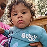 adult_hand, blue_outfit, bluey, casual_clothing, child, closeup, curly_hair, cute, daylight, expression, face, holding, outdoor, people, person, portrait, toddler, trees, wooden_rail, young_child