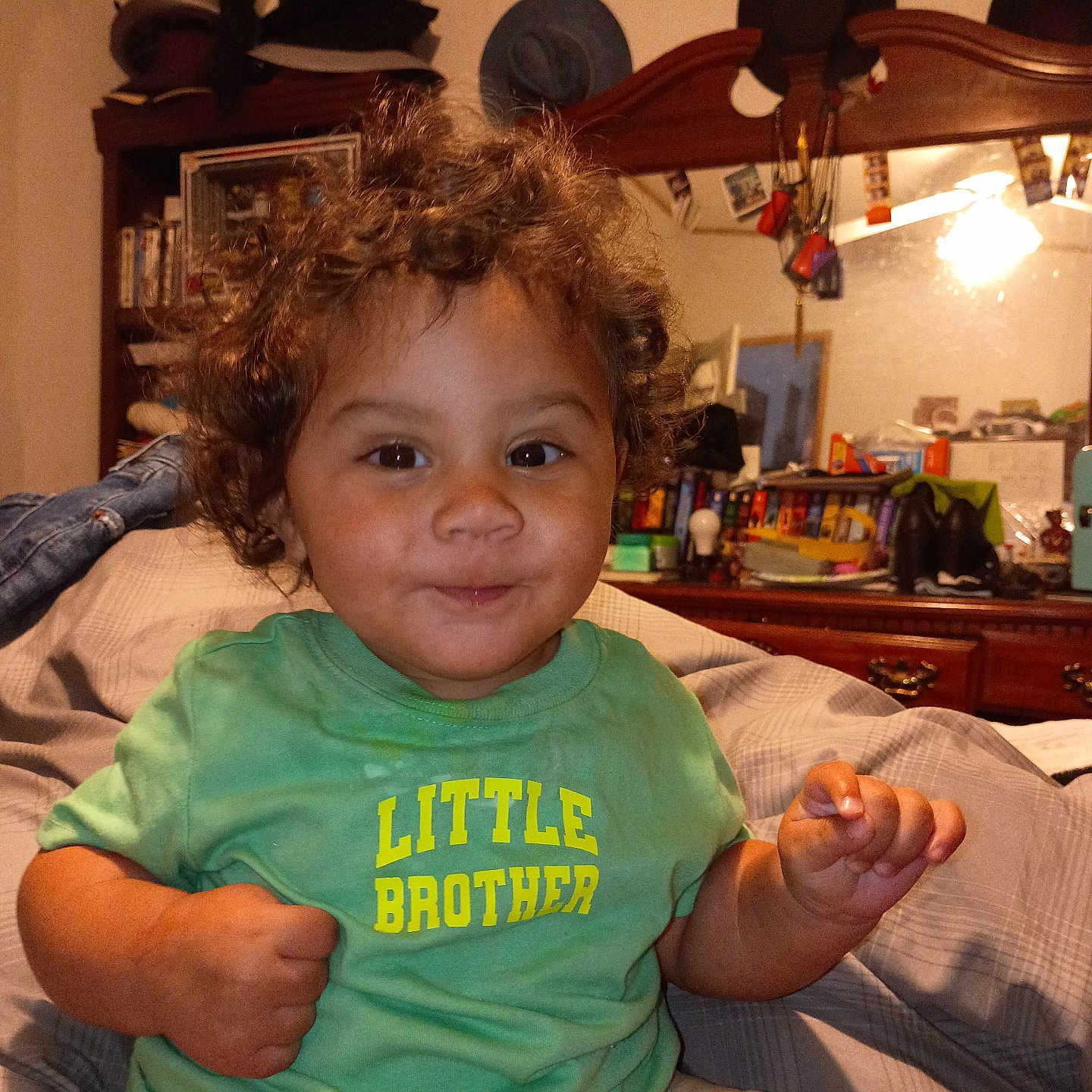 Arion joined the competition — help win amazing prizes! toddler, child, curly_hair, green_shirt, sitting, bed, indoor, smile, face, person, clothing, furniture, mirror, books, hat, room, cabinet, toy, head, portrait