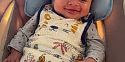 Elio a rejoint le concours — aidez-le/la à gagner de superbes lots ! baby, infant, smile, blanket, pacifier, seat, cushion, clothing, indoor, kitchen, face, hand, pattern, animal_print, comfort, child, young, cute, happy, portrait