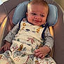 baby, infant, smile, blanket, pacifier, seat, cushion, clothing, indoor, kitchen, face, hand, pattern, animal_print, comfort, child, young, cute, happy, portrait