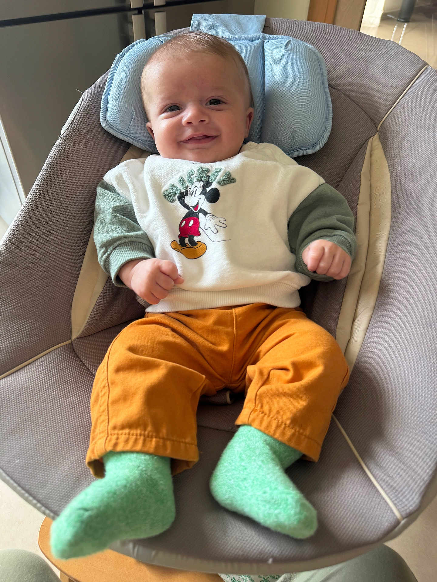 Elio participe au concours pour gagner de l'argent avec cette photo : baby, infant, smiling, mickey_mouse, sweater, pants, socks, baby_seat, indoor, child, cute, happy, portrait, clothing, comfortable, headrest, furniture, person, young_child, seated