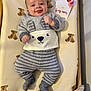 Elio participe au concours pour gagner de l'argent avec cette photo : baby, infant, smiling, tongue_out, clothing, gray_stripes, bear_face, mattress, teddy_bear_pattern, card, three_months, crib, blanket, cute, indoor, child, happy, lying_down, soft_toys, person