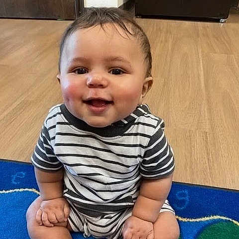 Kayden A joined the competition — help win amazing prizes! baby, child, colorful, eyes, face, floor, hair, hands, happy, home, indoors, infant, legs, onesie, play_mat, portrait, sitting, smiling, striped_clothing, wood_floor