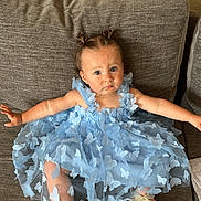 Kiara a rejoint le concours — aidez-le/la à gagner de superbes lots ! toddler, child, dress, blue_dress, butterflies, hair_buns, couch, golden_shoes, indoor, curious_expression, sitting, baby, fabric, textured_wall, footwear, cute, portrait, young_child, home, comfortable