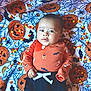 baby, black_pants, blanket, candy_corn, child, costume, cute, decorative, festive, halloween, holiday, indoors, infant, jack_o_lantern, lying_down, orange_clothing, portrait, soft_texture, spider_web, white_tie