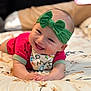 baby, smiling, headband, green_bow, lying_down, blanket, patterned, happy, infant, cute, clothing, toddler, face, portrait, indoors, skin, hands, fun, child, colorful