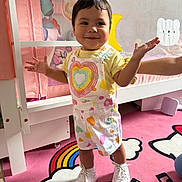 Daniela joined the competition — help win amazing prizes! toddler, child, smile, standing, overalls, sneakers, rainbow, musical_notes, pink_rug, playpen, toy, childrens_room, cute, happy, indoor, person, shorts, yellow_shirt, hand, face