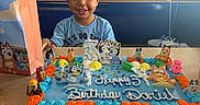 Dariel joined the competition — help win amazing prizes! child, birthday_cake, cake, bluey, balloon, arcade, party, celebration, smile, table, indoor, gift_bag, boy, colorful, icing, number_candle, toy_figures, happy, event, food