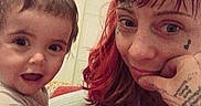 Alexandrite joined the competition — help win amazing prizes! child, woman, tattoos, bed, indoor, person, face, smile, curly_hair, red_hair, short_hair, expression, casual_clothing, hand, portrait, closeup, happy, toddler, interaction, home