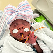 Lyliah is registered to the contest to win money with this photo: newborn, baby, hospital, medical_tape, feeding_tube, blanket, hat, striped_hat, swaddled, sleeping, infant, patient, healthcare, hand, cute, child, person, portrait, indoors, closeup