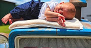 Hazel Faith is registered to the contest to win money with this photo: baby, sleeping, blanket, tractor, ford, blue, outdoor, sunny, sky, clouds, infant, clothing, white_shirt, pants, peaceful, resting, vintage, vehicle, farm, cute