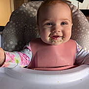 Ellie is registered to the contest to win money with this photo: baby, bib, high_chair, messy, food, face, smiling, child, infant, pink, clothing, indoor, person, happy, feeding, cute, portrait, young, seat, table