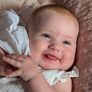 Ellie joined the competition — help win amazing prizes! baby, blanket, blue_eyes, cheeks, closeup, clothing, cuddly, cute, face, hands, happy, indoors, infant, joyful, portrait, skin, smiling, soft, white_dress, young_child