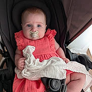 Ellie is registered to the contest to win money with this photo: baby, baby_clothing, blue_eyes, child, childcare, closeup, comfort, coral_dress, cute, furniture, hand, indoors, infant, legs, pacifier, portrait, seat_belt, soft_skin, stroller, white_cloth