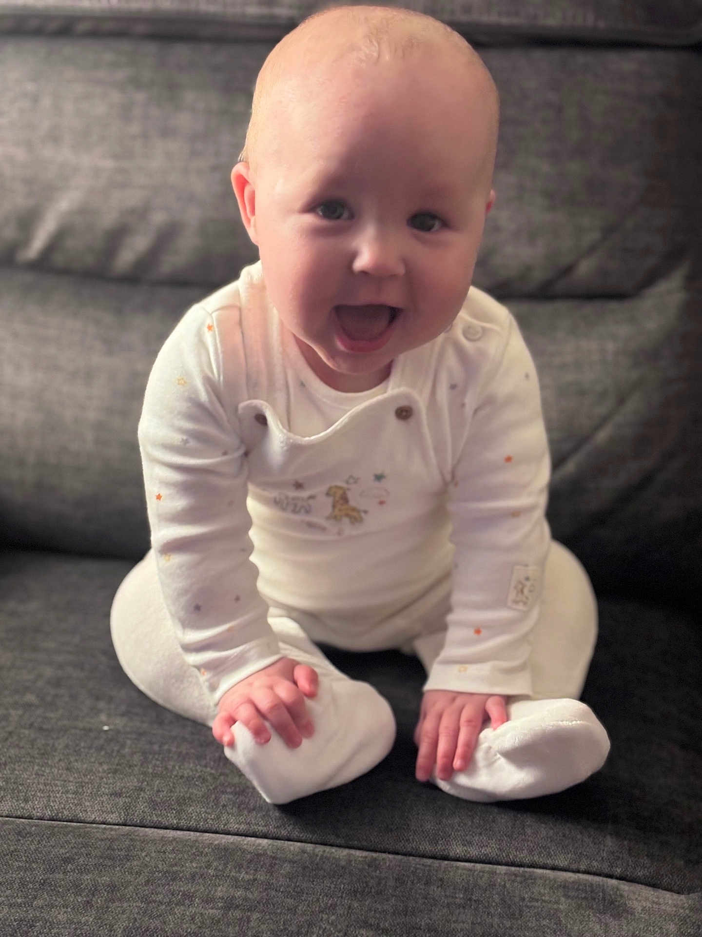 Olivia joined the competition — help win amazing prizes! baby, child, infant, smiling, happy, sitting, pajamas, white_clothing, couch, furniture, indoors, cute, young_child, face, hands, feet, cozy, portrait, expression, home