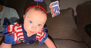 Lilah Jean is registered to the contest to win money with this photo: baby, child, blue_eyes, patriotic, red_white_blue, headband, antenna, couch, indoor, curious, infant, portrait, clothing, person, smiling, cute, face, toddler, home, celebration