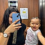 woman, toddler, child, mirror, selfie, elevator, phone, watch, tattoo, black_shirt, basketball_jersey, pink_clothing, smiling, braids, long_hair, casual, indoor, reflection, holding, playful