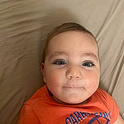 Viktor participe au concours pour gagner de l'argent avec cette photo : baby, bed, calm, casual, child, clothing, cute, expression, eyes, face, head, indoor, infant, laying, orange_shirt, person, portrait, sheet, skin, young