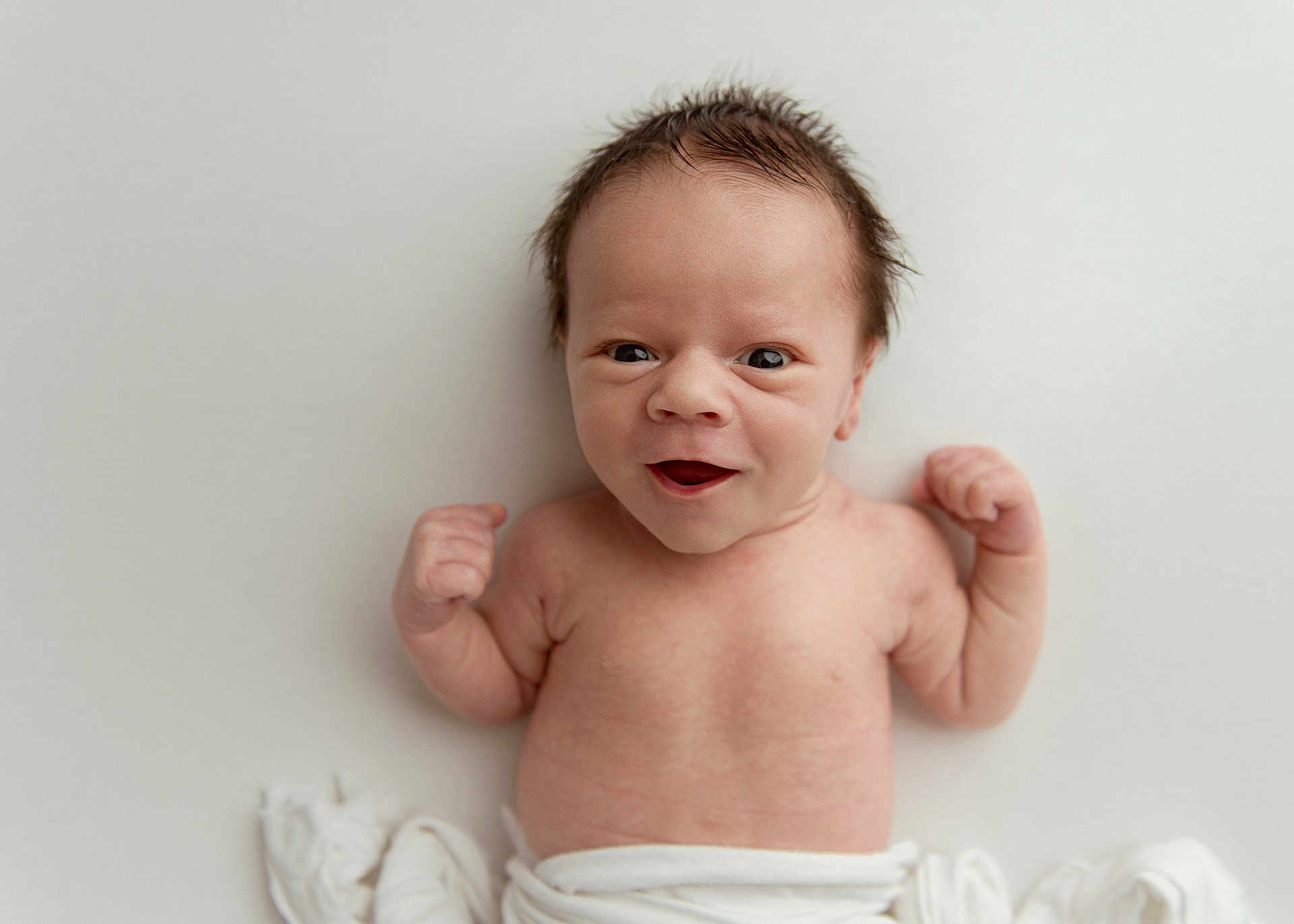 Archer is registered to the contest to win money with this photo: baby, newborn, infant, smiling, arms, flexing, hair, blanket, white, skin, cute, portrait, lying_down, expression, young, child, happy, face, person, toddler