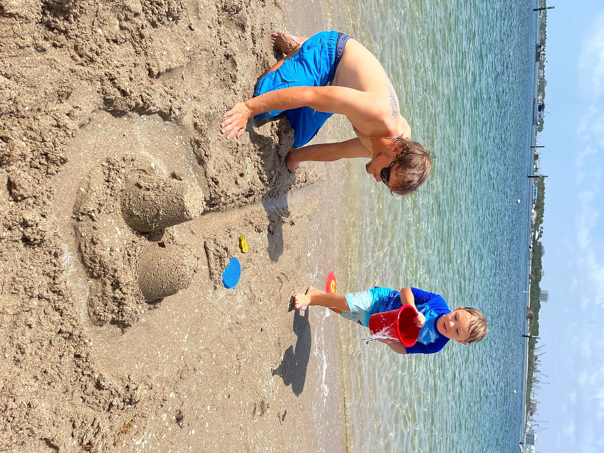 Quinton is registered to the contest to win money with this photo: adventure, barefoot, beach, blue, building_sand_castles, electric_blue, fun, happy, lake, leisure, outdoor_recreation, people_in_nature, people_on_beach, person, play, recreation, sand, sky, soil, travel