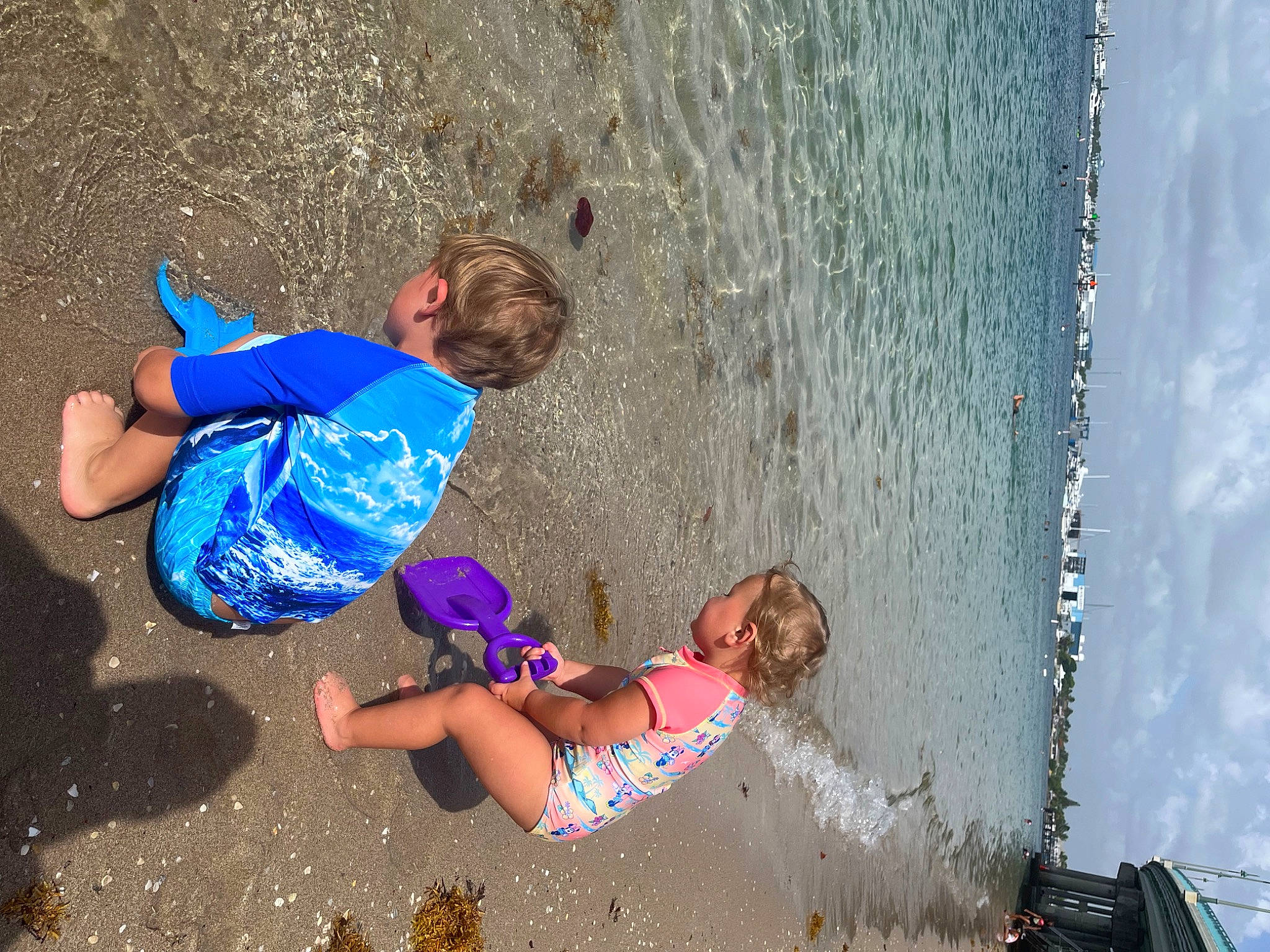 Quinton is registered to the contest to win money with this photo: azure, beach, body_of_water, child, fun, happy, human, leg, leisure, people_in_nature, people_on_beach, person, photograph, recreation, sand, shorts, summer, thigh, toddler, wall