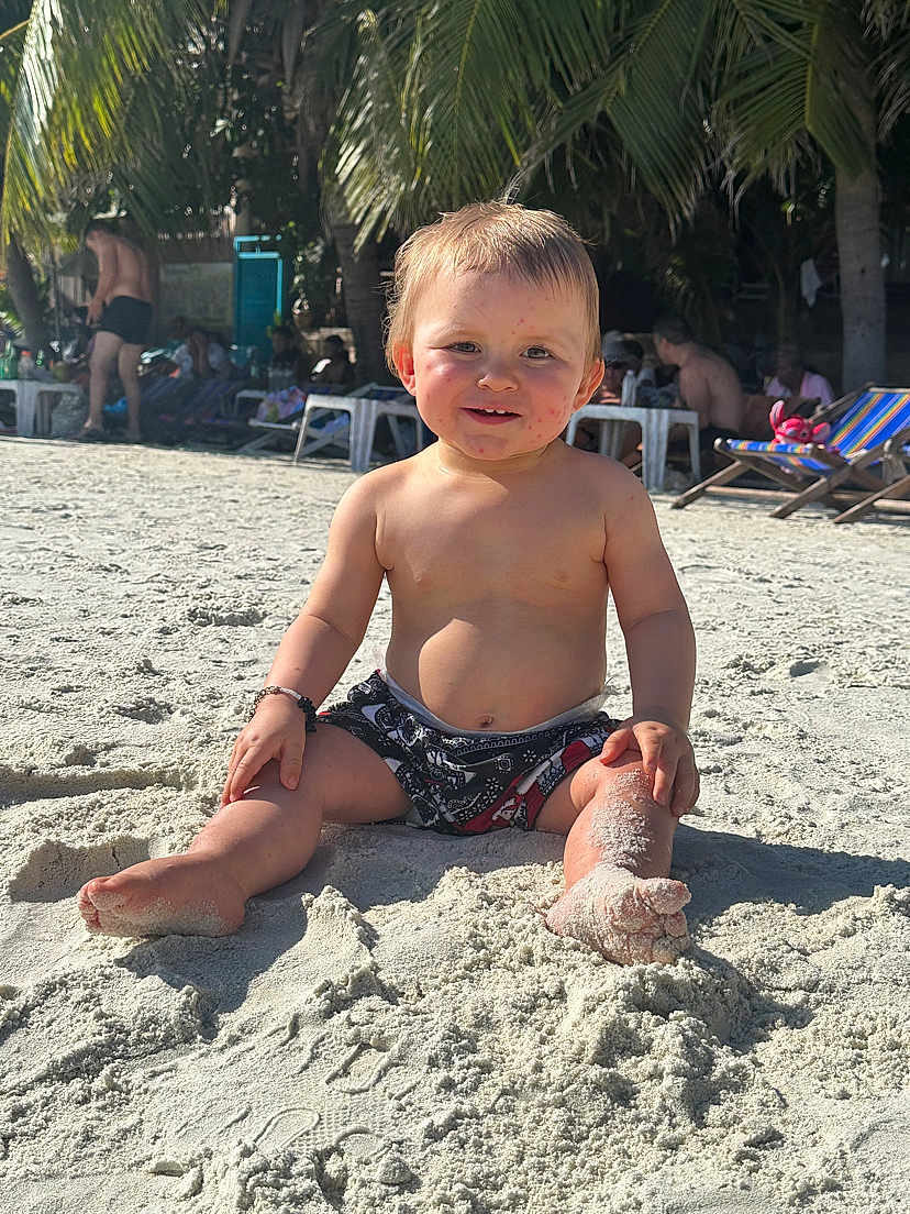 Thiago participe au concours pour gagner de l'argent avec cette photo : child, baby, beach, sand, sunlight, palm_trees, toddler, shorts, barefoot, smiling, outdoor, holiday, vacation, playing, summer, relaxing, people, nature, sand_on_skin, daytime