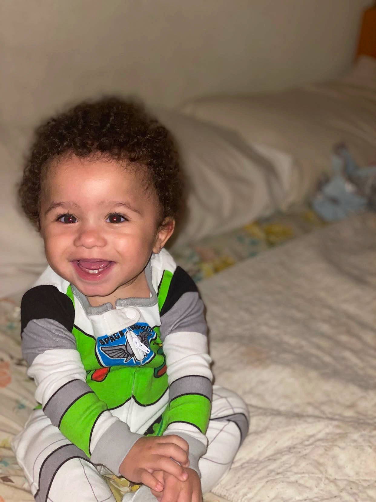 Kannon is registered to the contest to win money with this photo: baby, baby_toddler_clothing, bed, bed_sheet, bedding, bedroom, cheek, child, comfort, cool, facial_expression, happy, joy, laugh, linens, long_sleeved_t_shirt, person, pillow, skin, sock