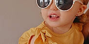 Ruby participe au concours pour gagner de l'argent avec cette photo : accessory, baby, casual, child, cute, earrings, face, fashion, happy, indoor, light_skin, person, portrait, ruffles, short_hair, smiling, summer, sunglasses, toddler, yellow_top