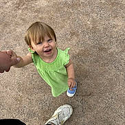 Ruby participe au concours pour gagner de l'argent avec cette photo : adult_hand, blue_shoe, casual, child, cute, daylight, footwear, green_dress, ground, happy, holding_hand, joyful, looking_up, outdoor, person, playful, smiling, toddler, white_sneaker, young_child