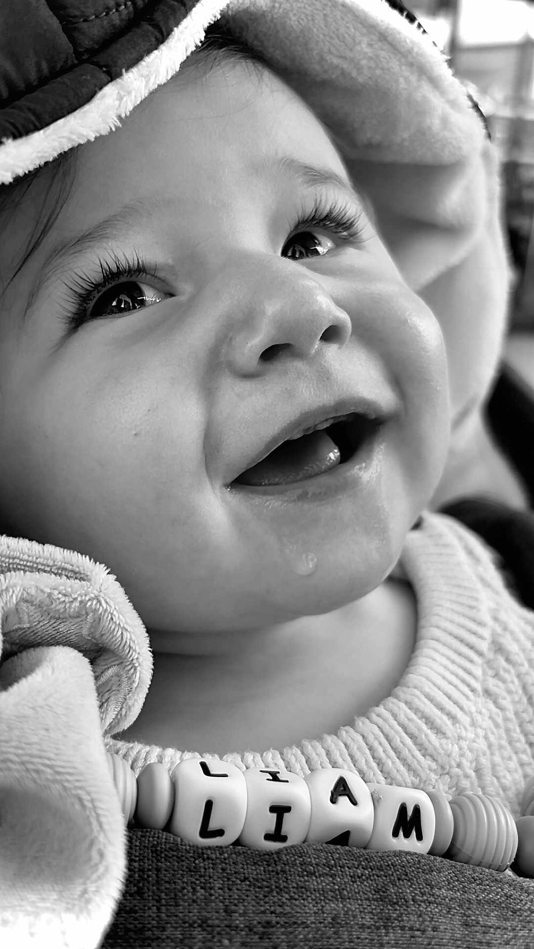 Liam a rejoint le concours — aidez-le/la à gagner de superbes lots ! baby, close_up, black_and_white, smiling, face, eyes, eyelashes, drool, beads, name_beads, fabric, clothing, portrait, child, cute, happy, infant, cozy, texture, soft